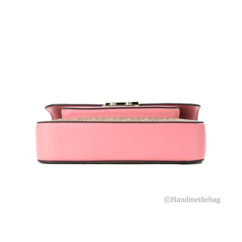 A rectangular pink Michael Kors Sloan Editor Leather Flap Crossbody Bag in Saffiano leather is shown from the bottom with gold hardware, displayed against a white background. The logo “@Handmethebag” appears in the lower right corner.