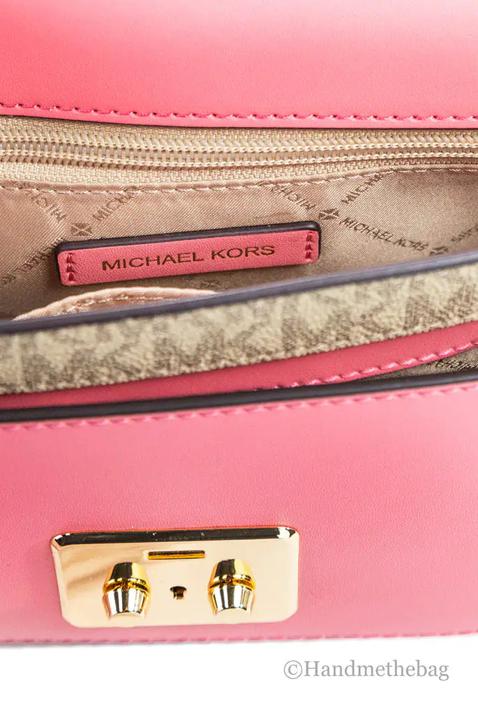 Close-up of an open pink Michael Kors Sloan Editor Leather Flap Crossbody Bag in Saffiano leather, with a gold clasp and interior brand tag. The lining has a subtle pattern and includes a beige zipper pocket.